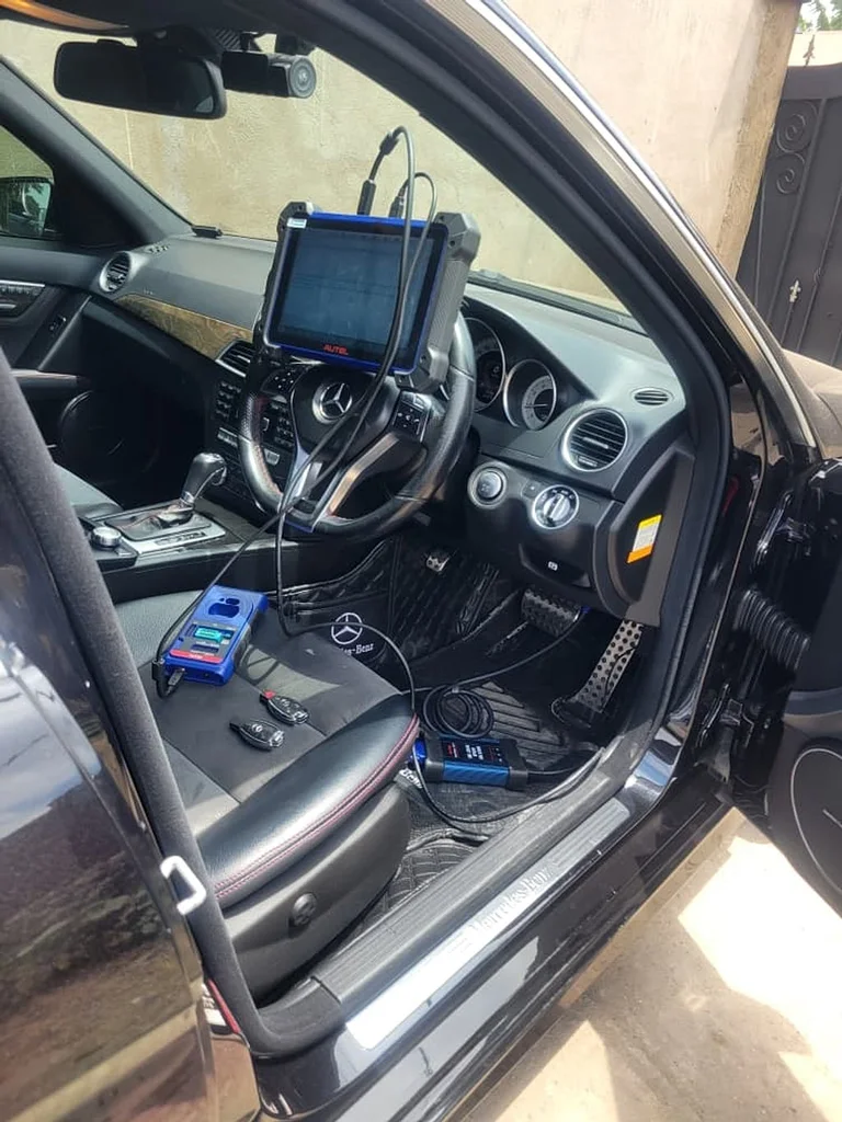Diagnostic tablet connected to a vehicle's OBD port, mounted on the steering wheel during a scan